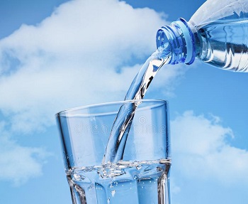 un verre est rempli par une bouteille d'eau