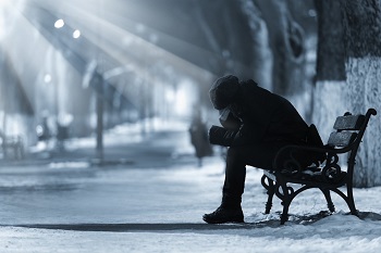 un homme seul et découragé assis sur un banc dans la nuit