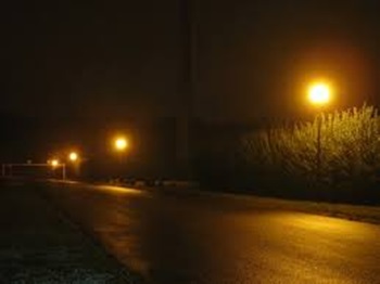 des lampadaires allumés dans une rue sombre